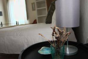 a lamp and a vase on a table next to a bed at Is Scabas Guestrooms in Solarussa