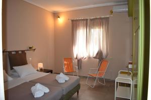 a bedroom with two beds and chairs and a window at Korina's Apartments in Ipsos