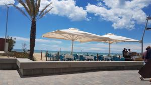 a patio with tables and umbrellas on the beach at BEACH & DREAMS CALAFELL in Calafell