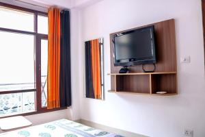 a room with a tv on a wall with a window at Sai Alok homestay in Shimla