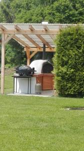 a barbecue under a wooden pergola in a yard at Ferienwohnung nahe Ulm/Laupheim in Laupheim
