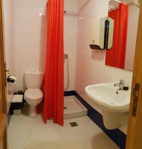 La salle de bains est pourvue de toilettes, d'un lavabo et d'un rideau de douche rouge. dans l'établissement Residencial Oscense, à Huesca