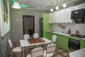 a kitchen with green cabinets and a table and chairs at Favorite apartment in Samarkand