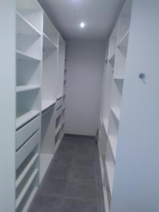 a walk in closet with white shelves and a tile floor at gite de Jade in Montaigu-de-Quercy