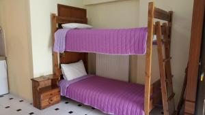 two bunk beds in a room with purple sheets at Studios Ermis in Kalamitsi