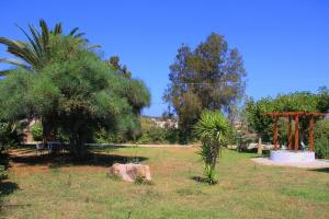 a park with a tree and a rock in the grass at Ilias Apartments in Methoni