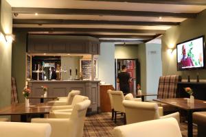 a restaurant with tables and chairs and a bar at Schooner Hotel in Alnmouth