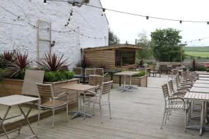 une rangée de tables et de chaises sur une terrasse en bois dans l'établissement Schooner Hotel, à Alnmouth