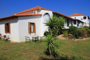 a white house with a table and chairs in a yard at Ilias Apartments in Methoni