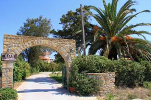 an archway in a park with a palm tree at Ilias Apartments in Methoni