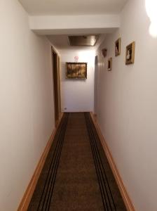 un largo pasillo con paredes blancas y alfombra en Pensiunea Liana, en Nemşa