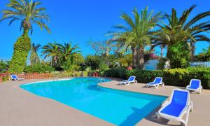 a swimming pool with chairs and palm trees at Cámping & Bungalows Estanyet in Les Cases d'Alcanar