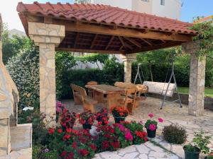 een paviljoen met een tafel en bloemen in een tuin bij Apartments Šime in Šibenik