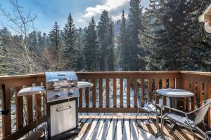 a grill and chairs on a deck with trees at Stonebrook Resort - Adult Only in Estes Park