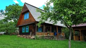a small log cabin with blue windows and a tree at Breb 418, Casa Opris in Breb