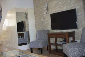 a living room with chairs and a television on a stone wall at Family Paradise- luxury combined with home comfort in Paphos City