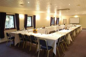 a conference room with tables and chairs and a screen at Healey House Hotel in Batley