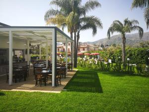 a patio with tables and chairs and palm trees at Residence Villa Giardini in Giardini Naxos