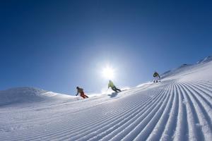 a group of three people skiing down a snow covered slope at Pension Rosenegg in Finkenberg