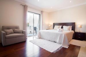 1 dormitorio con cama, sofá y ventana en Villa Ria Rose, Alto da Ria 23 - jacuzzi and beach, en Alvor