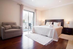 a bedroom with a bed and a couch and a window at Villa Ria Rose, Alto da Ria 23 - jacuzzi and beach in Alvor