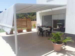 een patio met een witte luifel en een tafel en stoelen bij Villa Verde in Alcamo