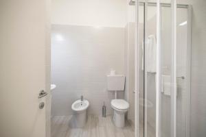 a white bathroom with a toilet and a shower at Hotel Continental in Caorle