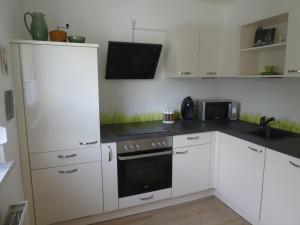 a kitchen with white cabinets and a black counter top at Ferienwohnung Mainz-Weisenau in Mainz