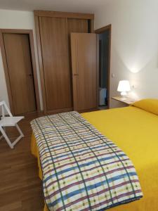 a bedroom with a yellow bed and a white chair at Apartamento Barbanza con plaza de garaje in Porto do Son