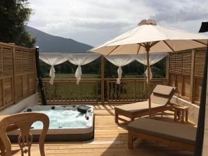 a hot tub on a deck with a chair and an umbrella at Villa Torrella in Mezzavia
