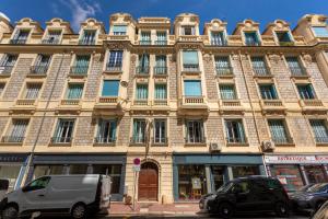 un grande edificio con macchine parcheggiate di fronte di Nice Home - Studios Lido a Nizza