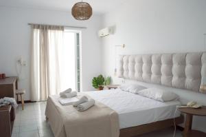 a white bedroom with a large white bed with towels on it at Paradise Beach Hotel in Argasi