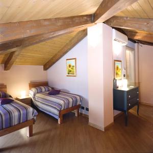 2 letti in una camera con soffitti in legno di Tenuta Roletto a Cuceglio