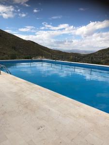 uma grande piscina azul com montanhas ao fundo em Cortijo El Rancho em Albánchez