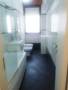 a white bathroom with two toilets and a window at Open Space Aldobrandini in Lido di Ostia +8 photos