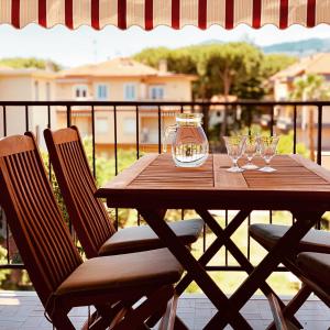 uma mesa de madeira com copos de vinho e um guarda-chuva em Bordighera vicino al mare em Bordighera