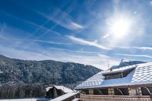 莫爾濟訥的住宿－Nant Morzine，一座建筑物的雪盖屋顶,阳光照耀着天空