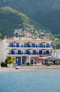 un gran edificio blanco con ventanas azules junto al agua en KAMVISSIS HOTEL en Tiros