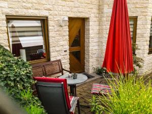 een patio met een tafel en 2 rode parasols bij Mosel-Ferienwohnung Berhard in Bruttig-Fankel
