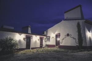 um edifício branco com duas portas à noite em Casas da Faia - Nature Guest House em Arronches