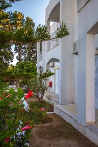 un edificio bianco con alberi e fiori di fronte di Irene Hotel Leros ad Alinda