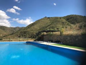 uma grande piscina azul com uma montanha ao fundo em Cortijo El Rancho em Albánchez