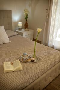 einen Teller mit einem Buch und eine Vase mit einer Blume auf dem Bett in der Unterkunft B&B L'Arca Di Noè in La Spezia