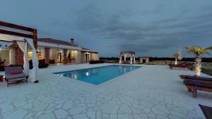 a swimming pool with two chairs and a house at Villa Melody Novalja in Novalja