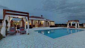 a swimming pool with two chairs and a gazebo at Villa Melody Novalja in Novalja