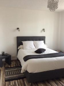 Schlafzimmer mit einem Bett mit weißer Bettwäsche und einem Kronleuchter in der Unterkunft Le Clément'Inn in Noyers-sur-Cher