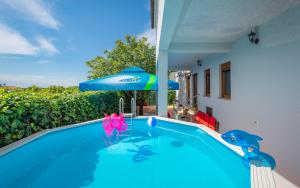 a swimming pool with a blue umbrella and a house at Apartman Summer Breeze in Marčana
