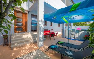 eine Terrasse mit einem blauen Sonnenschirm, einem Tisch und Stühlen in der Unterkunft Apartman Summer Breeze in Marčana