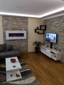 a living room with a couch and a tv on a brick wall at Apartman Maximus Zlatibor in Zlatibor
