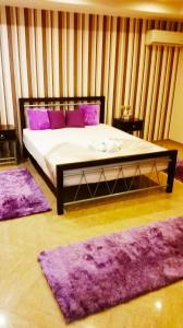 ein Schlafzimmer mit einem Bett mit lila Kissen und zwei lila Teppichen in der Unterkunft Kate's & Kallia's House in Kefalos